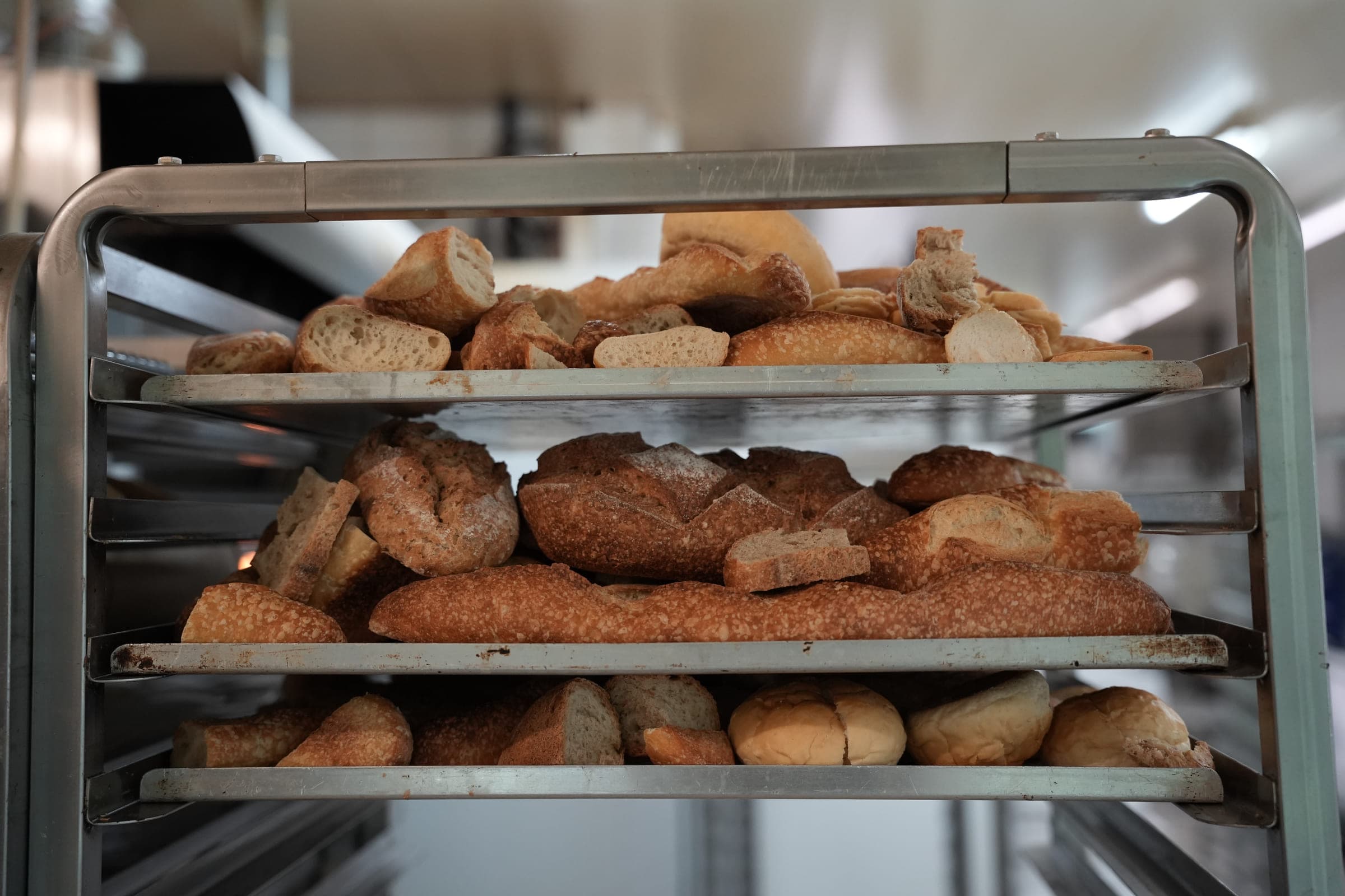 Trois clayettes d’une échelle de boulanger chargées de miches complètes, de pains ronds et de petits pains.